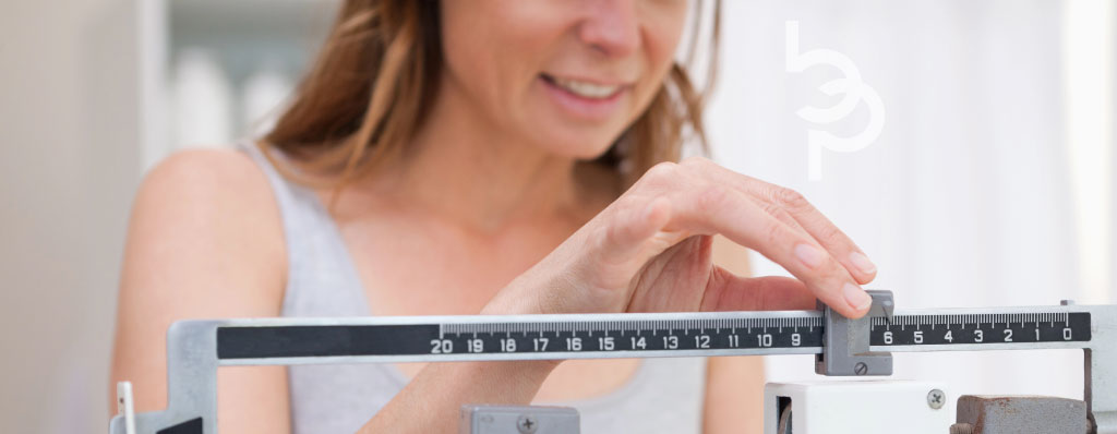 Mature lady weighing self and confident that she's well on her way to her weight loss goals.